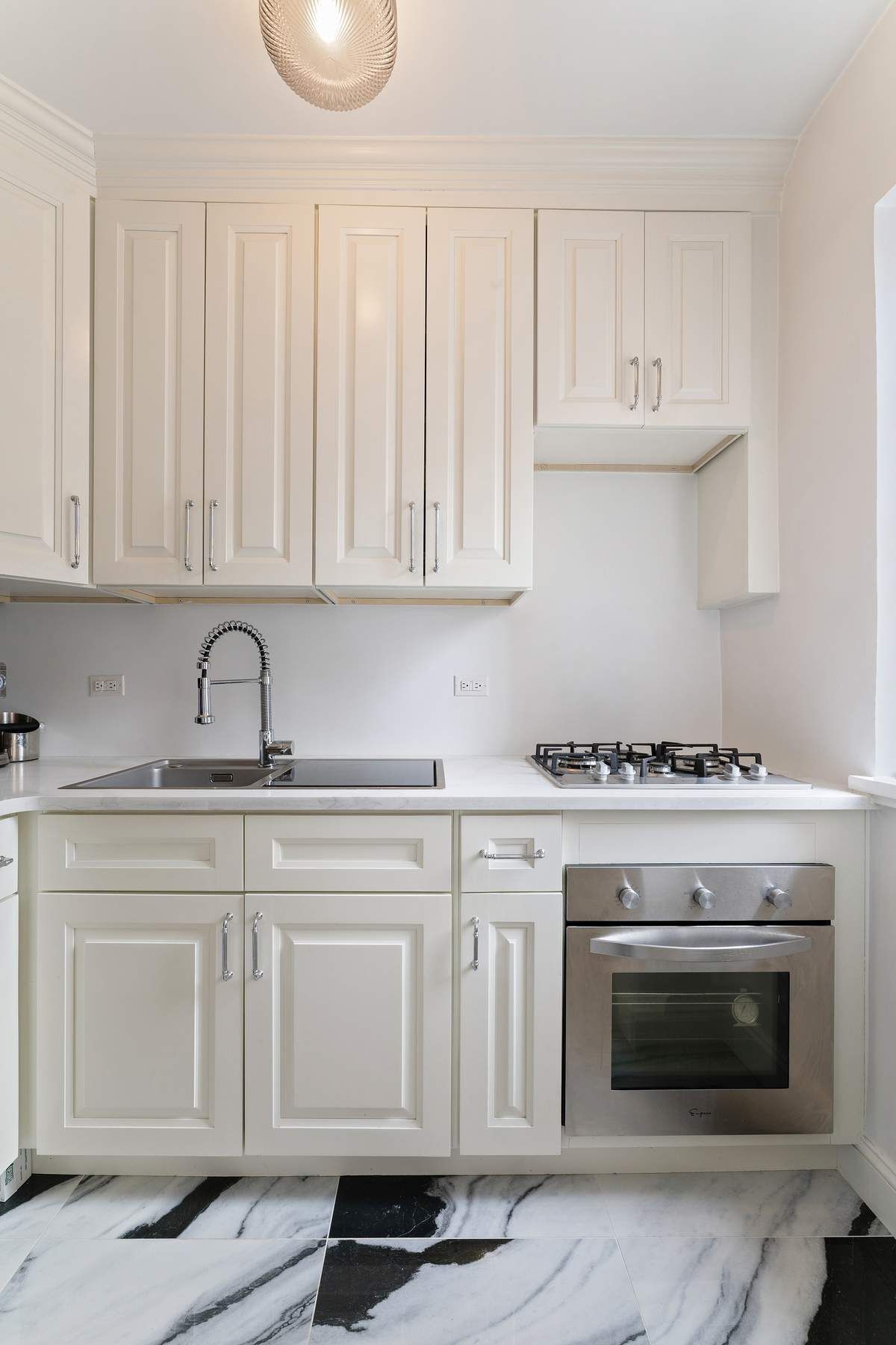 10 Park Avenue, Unit 10R Manhattan, NY 10016 - Photo 5 of 9 a kitchen with white cabinets and a stove top oven