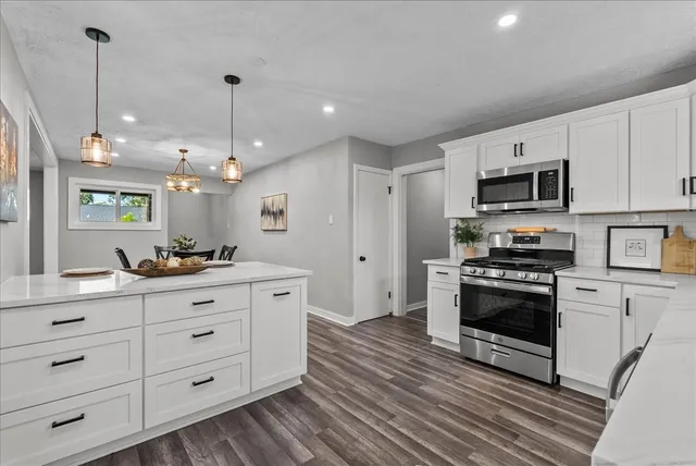 a kitchen with stainless steel appliances kitchen island granite countertop a stove a sink and a refrigerator