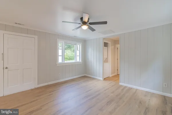 an empty room with wooden floor ceiling fan and windows