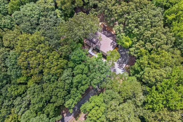 an aerial view of residential house with outdoor space and trees all around