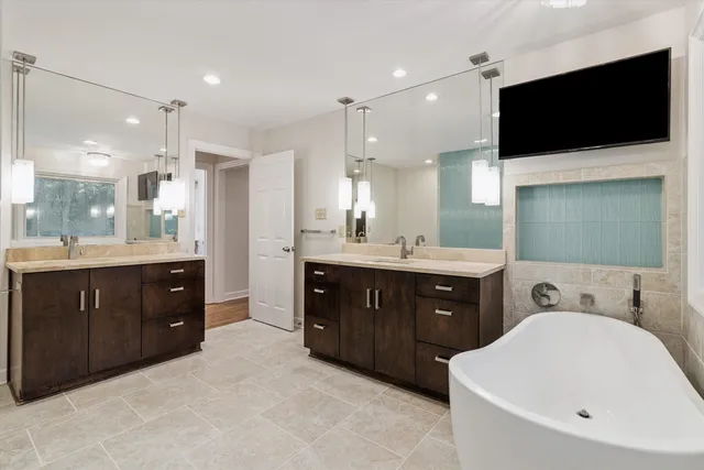 a spacious bathroom with a double vanity sink a mirror and a bathtub