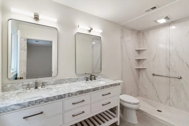 a bathroom with a granite countertop sink toilet and shower