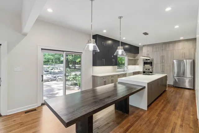 a kitchen with stainless steel appliances granite countertop a stove a sink a refrigerator and wooden floor