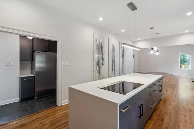 a kitchen with kitchen island a refrigerator and a sink
