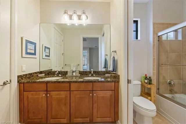 a bathroom with a granite countertop sink toilet and mirror