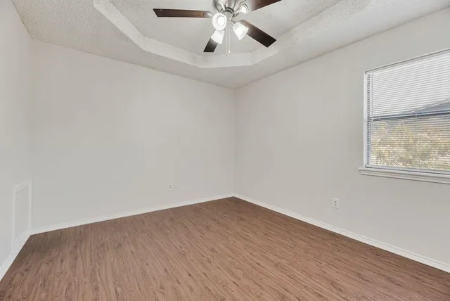 a view of an empty room with wooden floor and a window