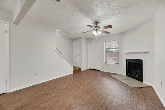 an empty room with wooden floor fireplace and windows