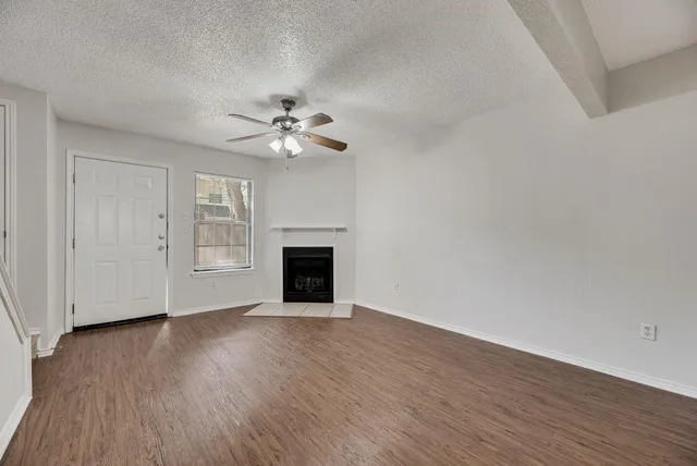 a view of an empty room with a fireplace and wooden floor