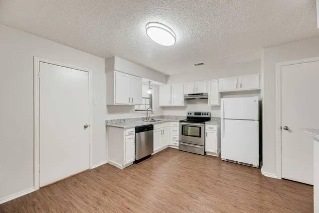 a kitchen with a refrigerator stove and wooden floor