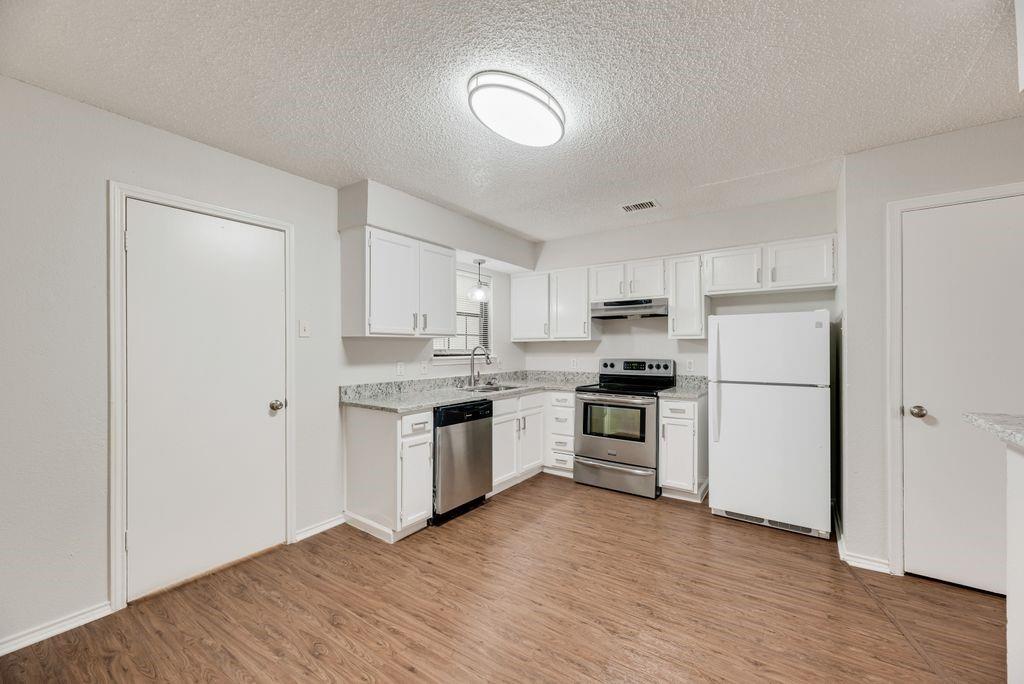 648 South Rogers Road, Unit 650 Irving, TX 75060 - Photo 8 of 21 a kitchen with a refrigerator stove and wooden floor