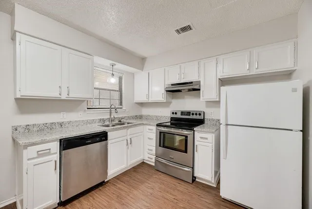 a kitchen with cabinets appliances a sink and a window