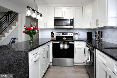 a kitchen with stainless steel appliances granite countertop a sink a stove and a granite counter top