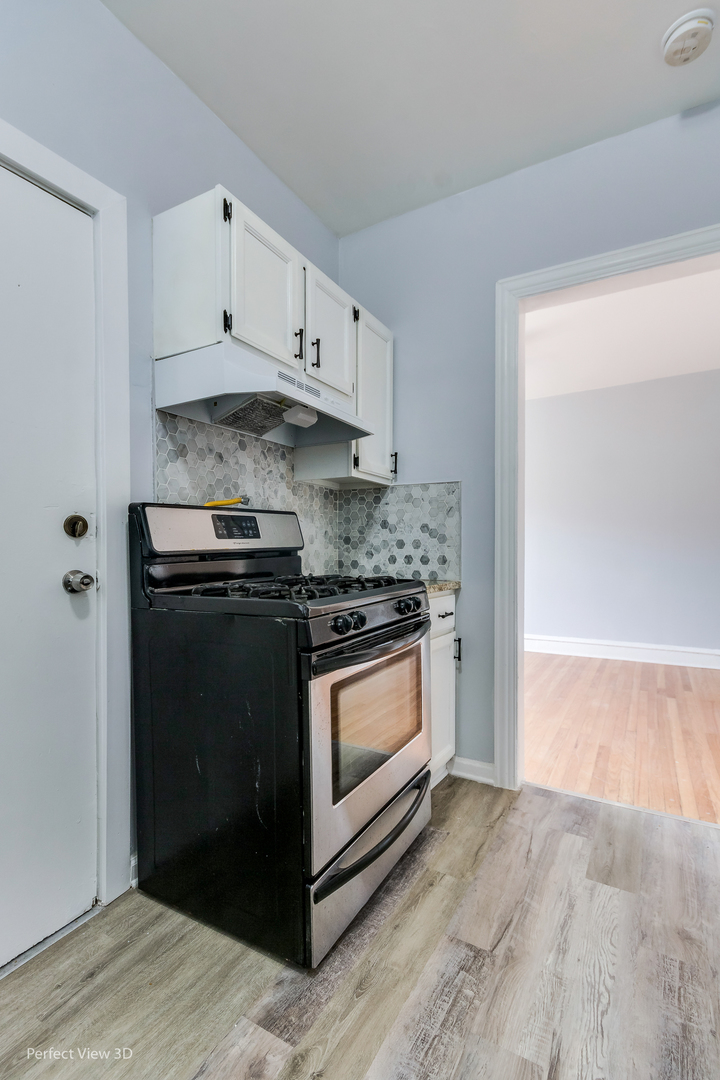 2212 East 70th Street, Unit 3D Chicago, IL 60649 - Photo 12 of 21 a kitchen with granite countertop white cabinets and stainless steel appliances