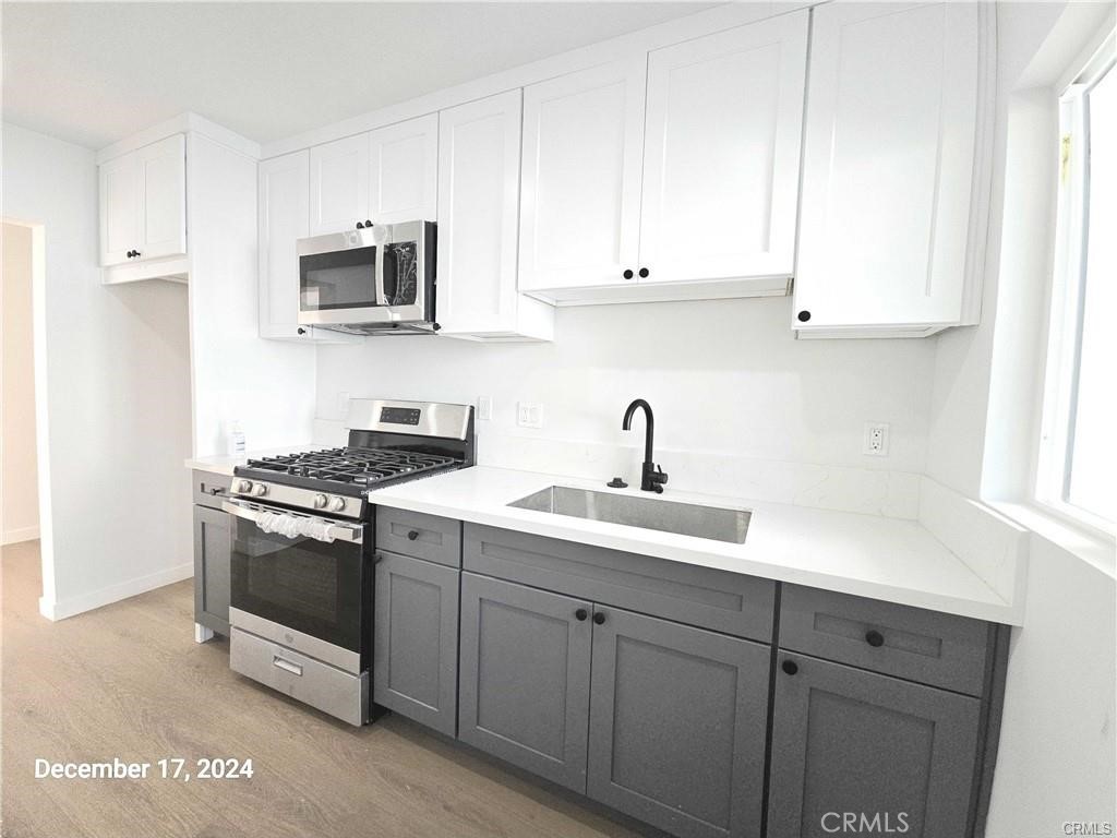 11171 Bullis Road Lynwood, CA 90262 - Photo 6 of 15 a kitchen with white cabinets and stainless steel appliances