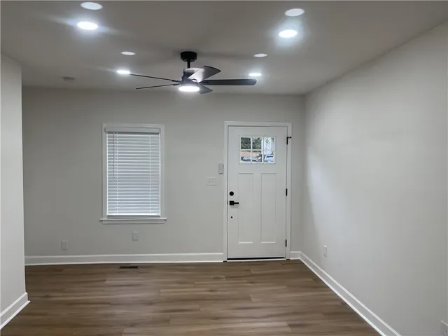 an empty room with wooden floor chandelier fan and windows