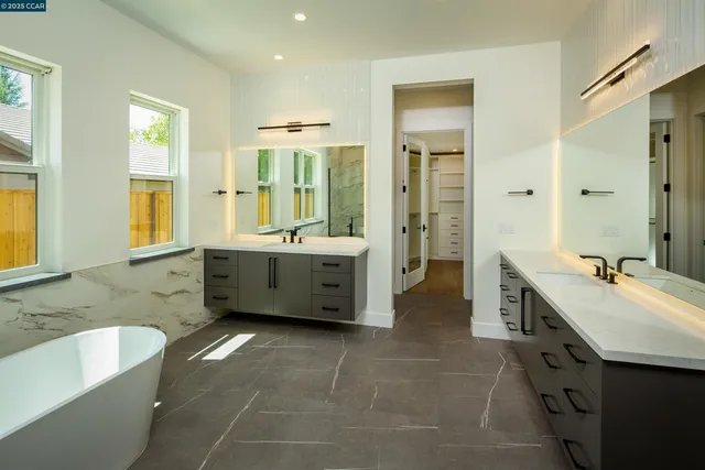 a spacious bathroom with a tub sink and mirror