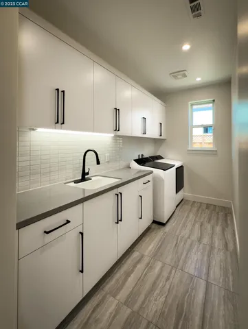 a kitchen with white cabinets and sink