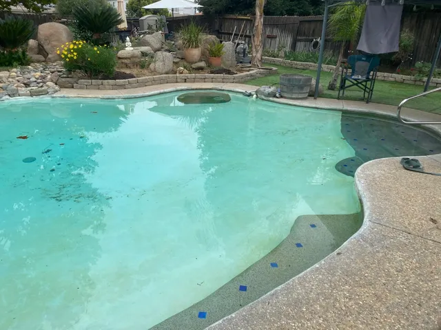 a view of a swimming pool with a bench and lawn chairs