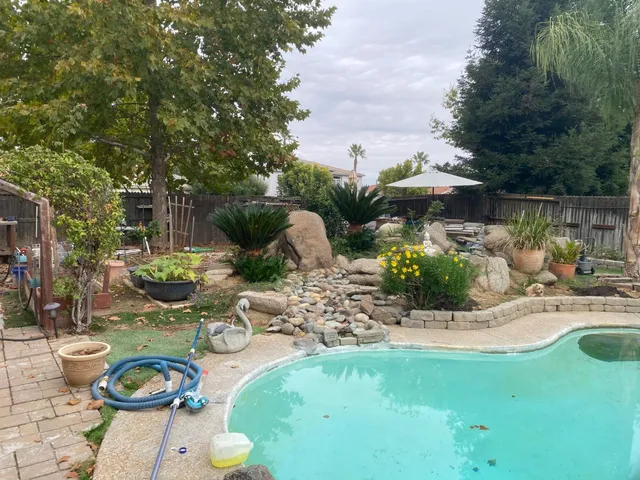 a view of a swimming pool with lawn chairs under an umbrella