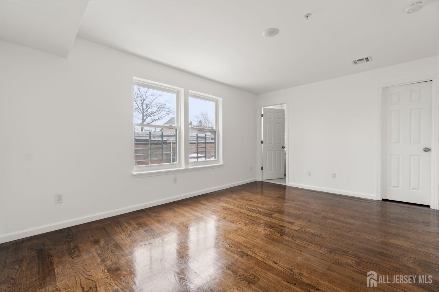 496 South 18th Street, Unit 2 Newark, NJ 07103 - Photo 17 of 21 a view of an empty room with wooden floor and a window