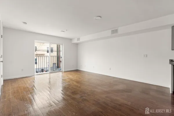 a view of an empty room with a window and wooden floor