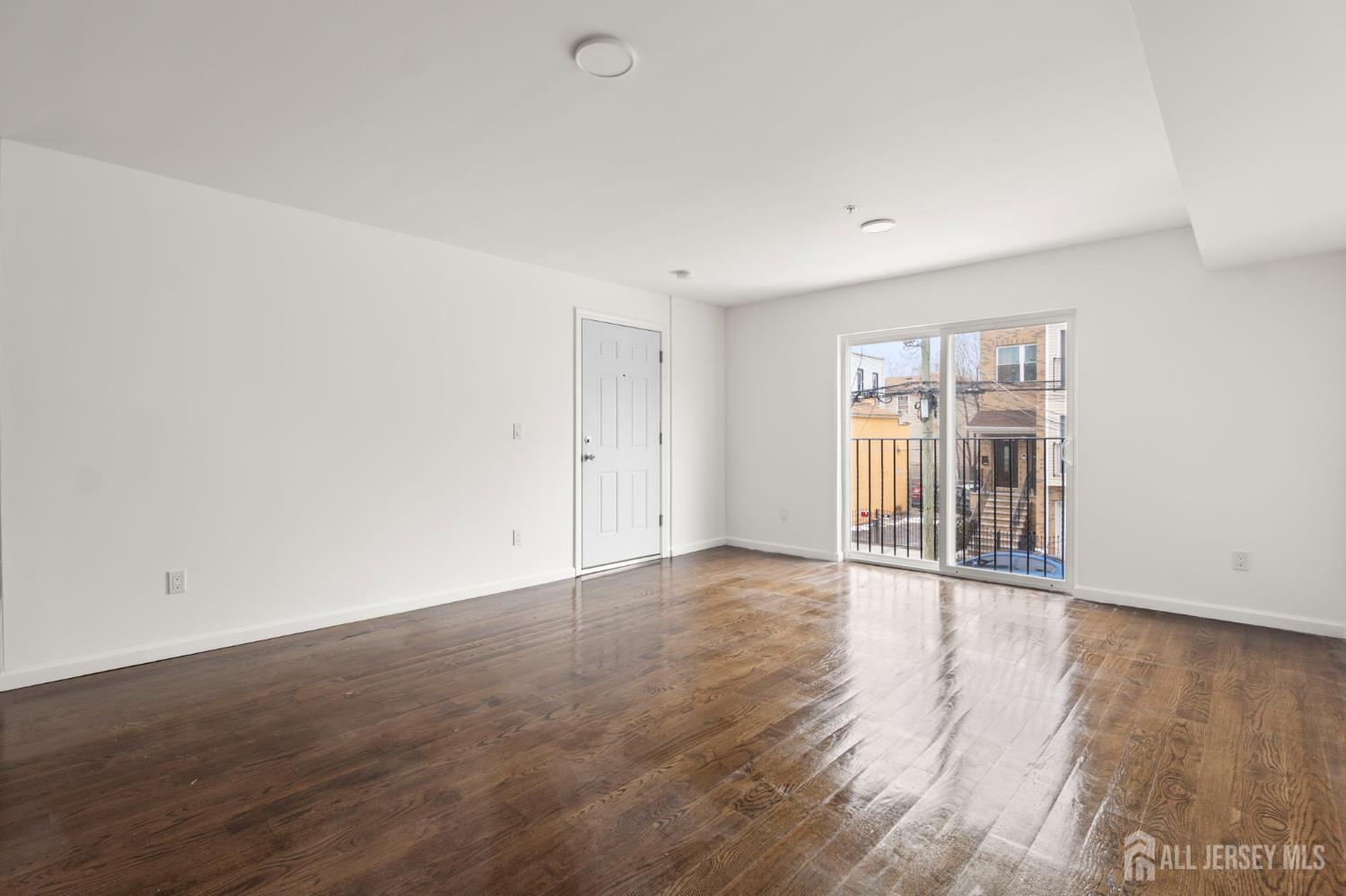 496 South 18th Street, Unit 2 Newark, NJ 07103 - Photo 3 of 21 a view of an empty room with wooden floor and a window