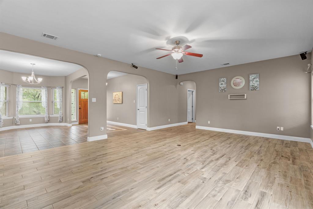 217 Naibara Trail Weatherford, TX 76088 - Photo 12 of 40 a view of an empty room with wooden floor and a kitchen