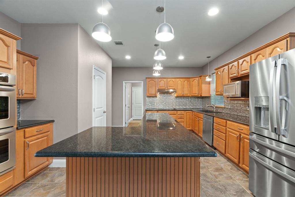 217 Naibara Trail Weatherford, TX 76088 - Photo 7 of 35 a kitchen with stainless steel appliances granite countertop a sink a stove and a microwave