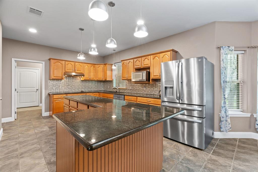 217 Naibara Trail Weatherford, TX 76088 - Photo 7 of 40 a kitchen with stainless steel appliances granite countertop a refrigerator a sink dishwasher a oven and a dining table with wooden floor