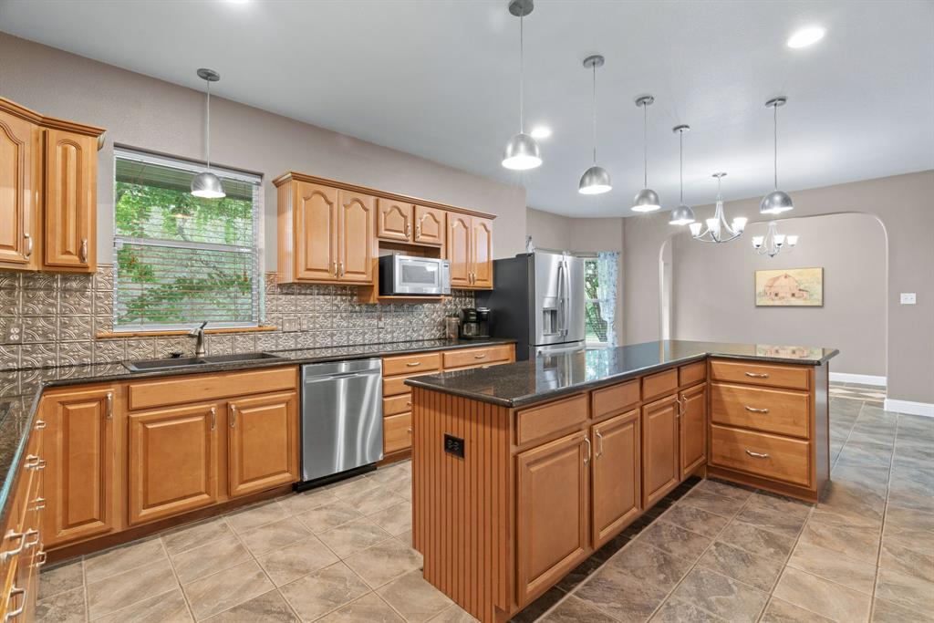 217 Naibara Trail Weatherford, TX 76088 - Photo 9 of 40 a kitchen with kitchen island granite countertop a large counter top sink stainless steel appliances and cabinets