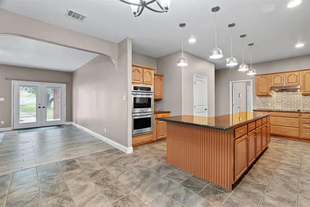 a view of a kitchen with kitchen island granite countertop a refrigerator and a stove