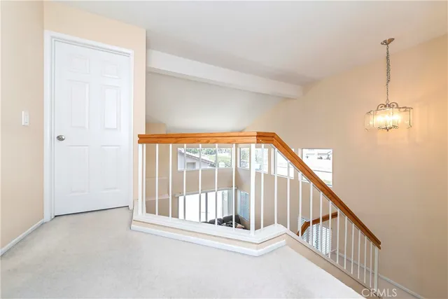 a view of staircase with railing and a chandelier