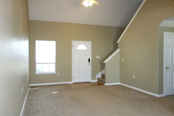 a view of an empty room with chandelier fan