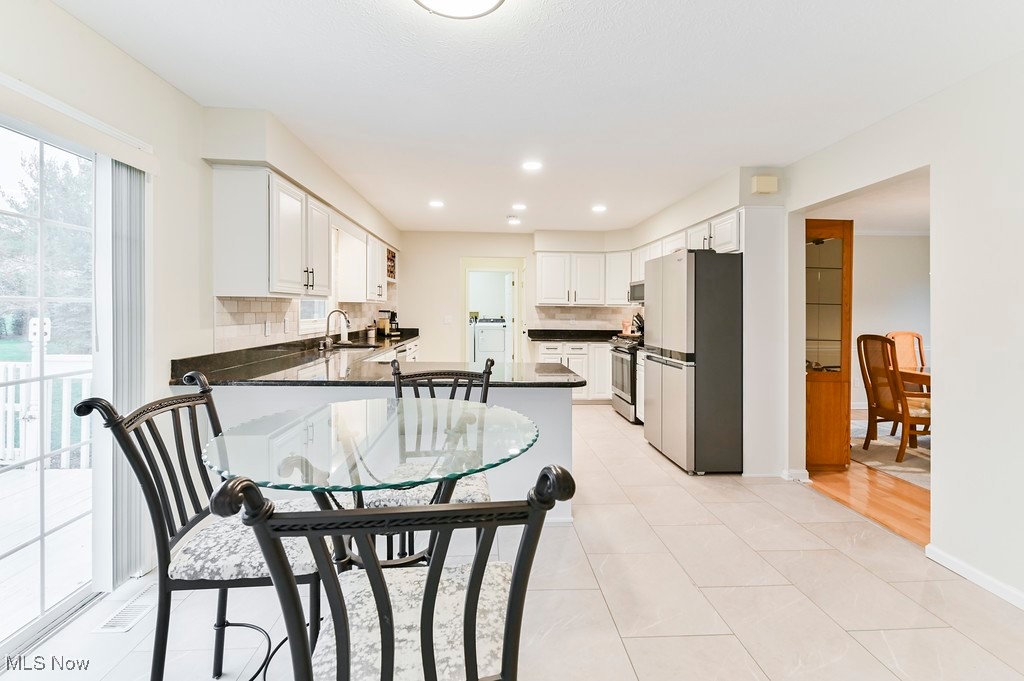 482 Longspur Road Highland Heights, OH 44143 - Photo 17 of 47 Kitchen featuring decorative backsplash, a sink, dark countertops, a peninsula, and appliances with stainless steel finishes