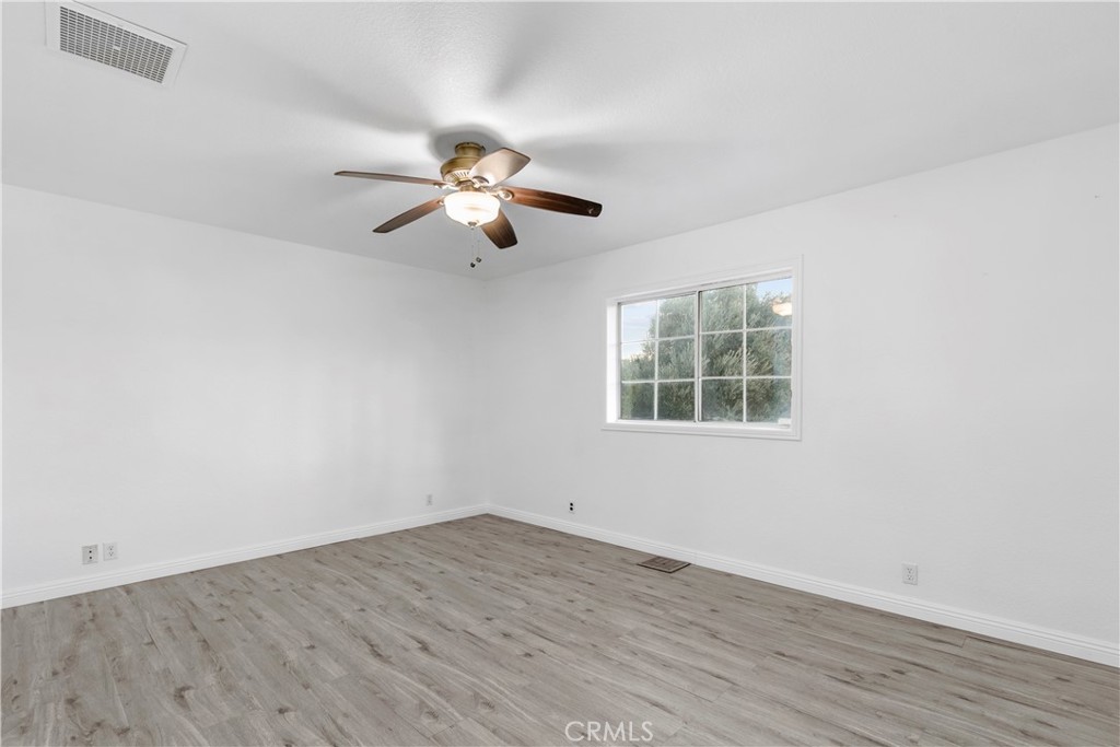 68295 Marina Road Cathedral City, CA 92234 - Photo 11 of 39 an empty room with wooden floor ceiling fan and windows