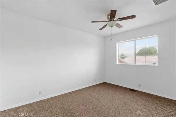 an empty room with a window and a fan