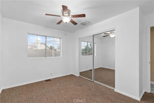 an empty room with windows and fan