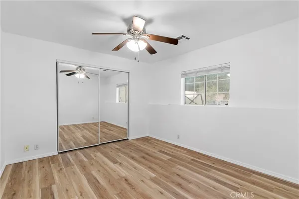 a view of empty room with wooden floor and fan