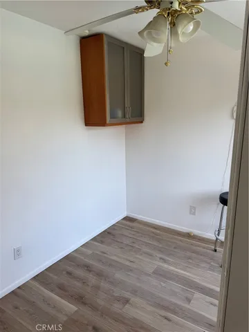 a view of an empty room with wooden floor and cabinet