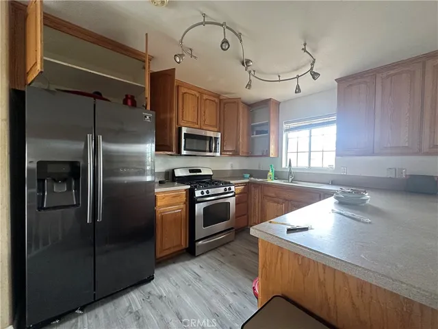 a kitchen with granite countertop a refrigerator a sink a stove and cabinets