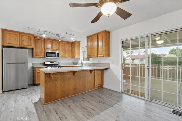 a kitchen with stainless steel appliances granite countertop a refrigerator a stove top oven a sink and a wooden floor