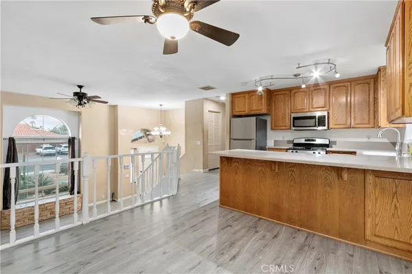 a kitchen with stainless steel appliances granite countertop a refrigerator a sink dishwasher a stove and white cabinets with wooden floor