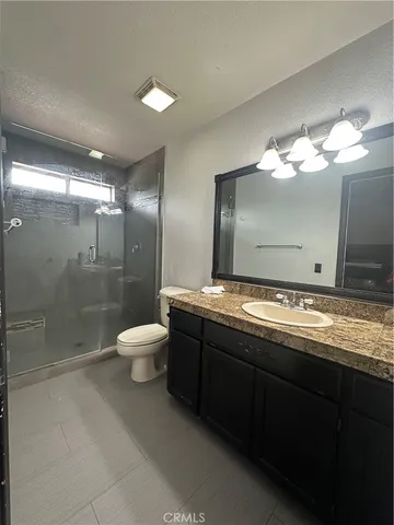 a bathroom with a granite countertop sink a toilet and a shower