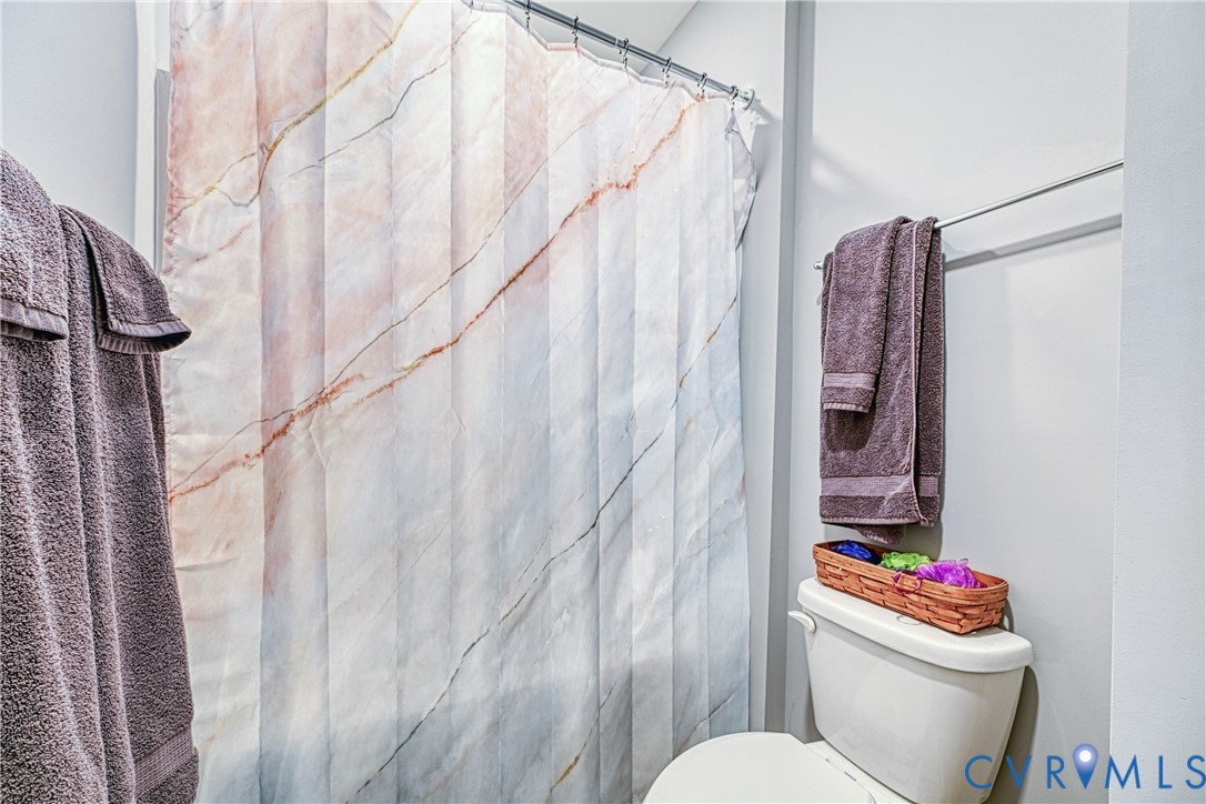 1009 Woodlet Meadow Lane Richmond, VA 23236 - Photo 33 of 44 a white toilet sitting next to a shower curtain