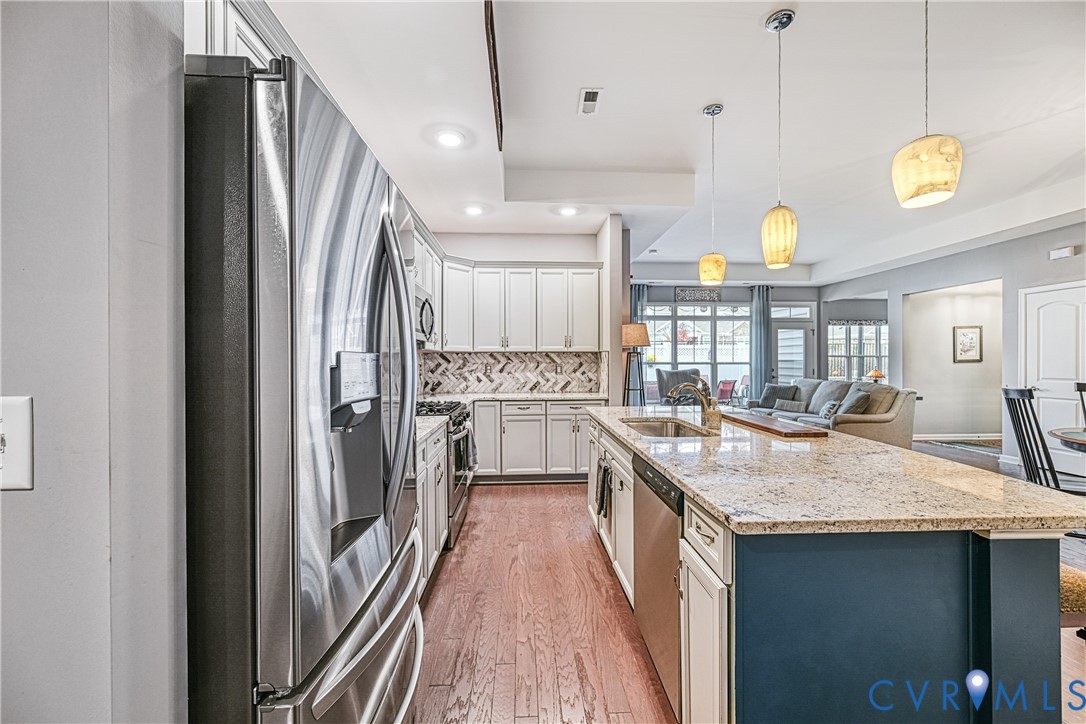 1009 Woodlet Meadow Lane Richmond, VA 23236 - Photo 6 of 44 a kitchen with stainless steel appliances granite countertop a refrigerator a sink dishwasher a stove and white cabinets with wooden floor