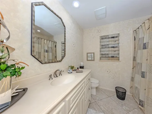 a bathroom with a granite countertop sink a toilet and a mirror