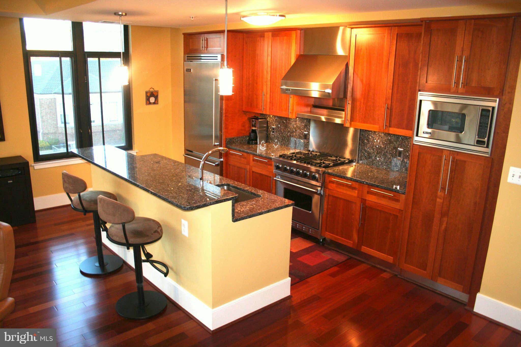 4301 Military Road Northwest, Unit 514 Washington, DC 20015 - Photo 9 of 29 a kitchen with stainless steel appliances granite countertop wooden cabinets a stove a sink and a refrigerator