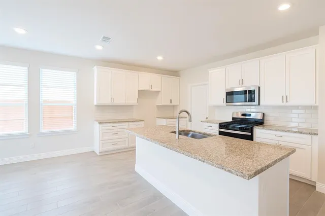 a kitchen with stainless steel appliances granite countertop a sink stove and cabinets