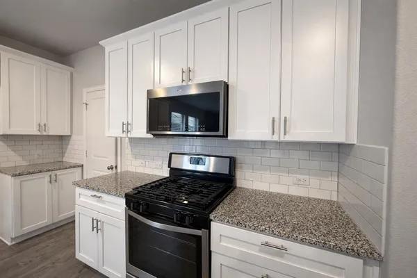 a kitchen with stainless steel appliances granite countertop white cabinets and a stove