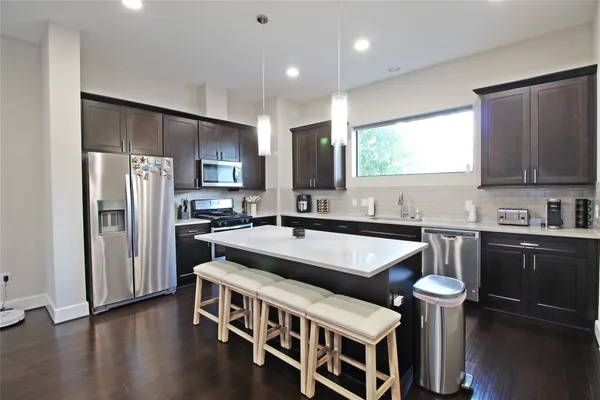 a kitchen with stainless steel appliances granite countertop a sink a stove a refrigerator and cabinets